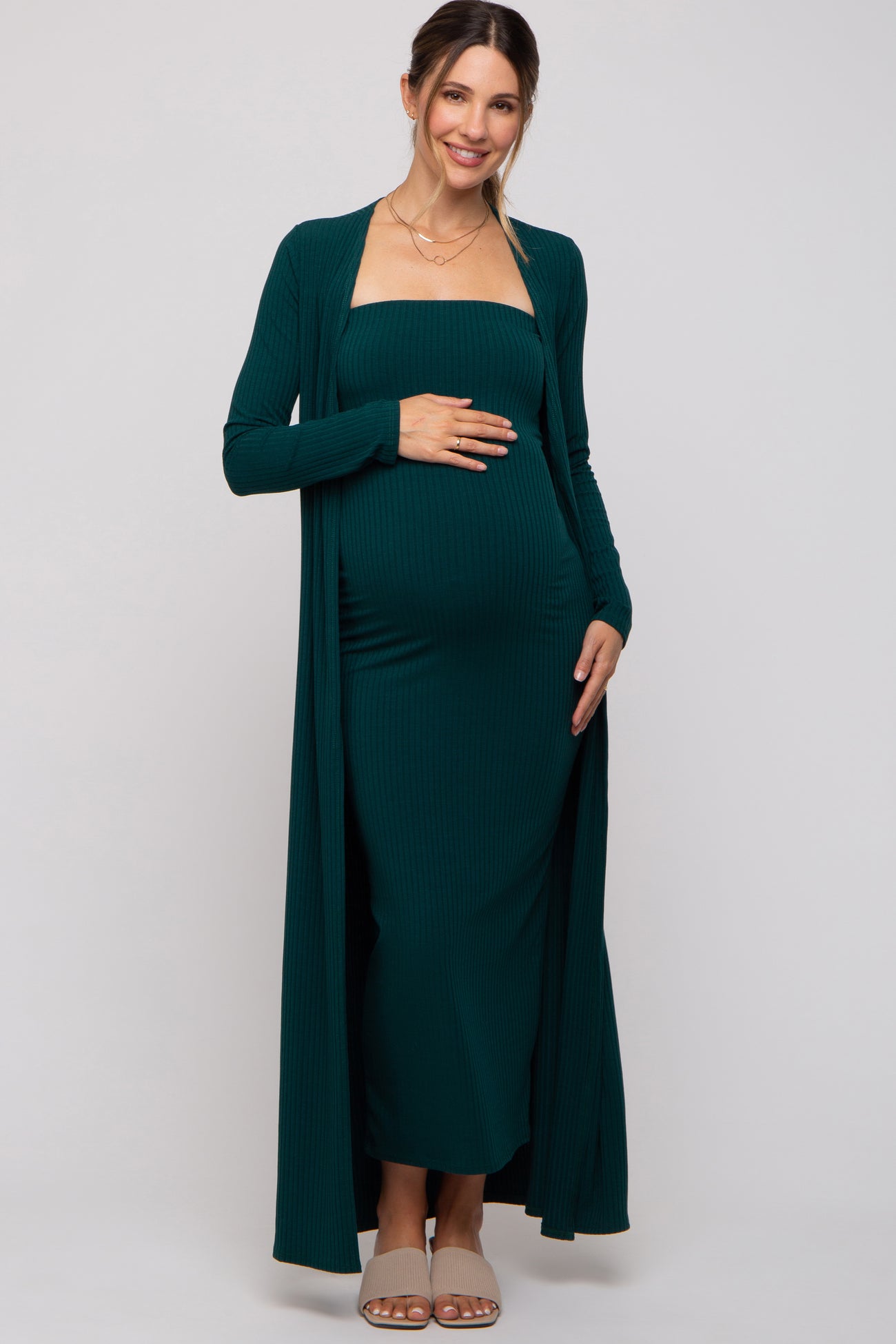 woman wearing a dark green maternity ribbed maxi dress with a matching cardigan and showing her baby bump