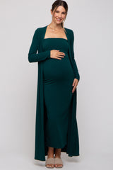 woman wearing a dark green maternity ribbed maxi dress with a matching cardigan and showing her baby bump