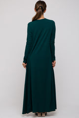 woman wearing a dark green long sleeve maternity dress, seen from the back with a flowy silhouette
