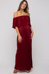 woman wearing a burgundy off-the-shoulder maternity dress with ruffle detail and a visible baby bump