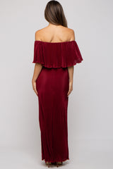 woman wearing a burgundy off-the-shoulder maternity maxi dress with a flowing ruffle detail at the neckline