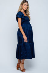 woman wearing a navy blue maternity dress with ruffle sleeves and a tiered skirt, showing her baby bump