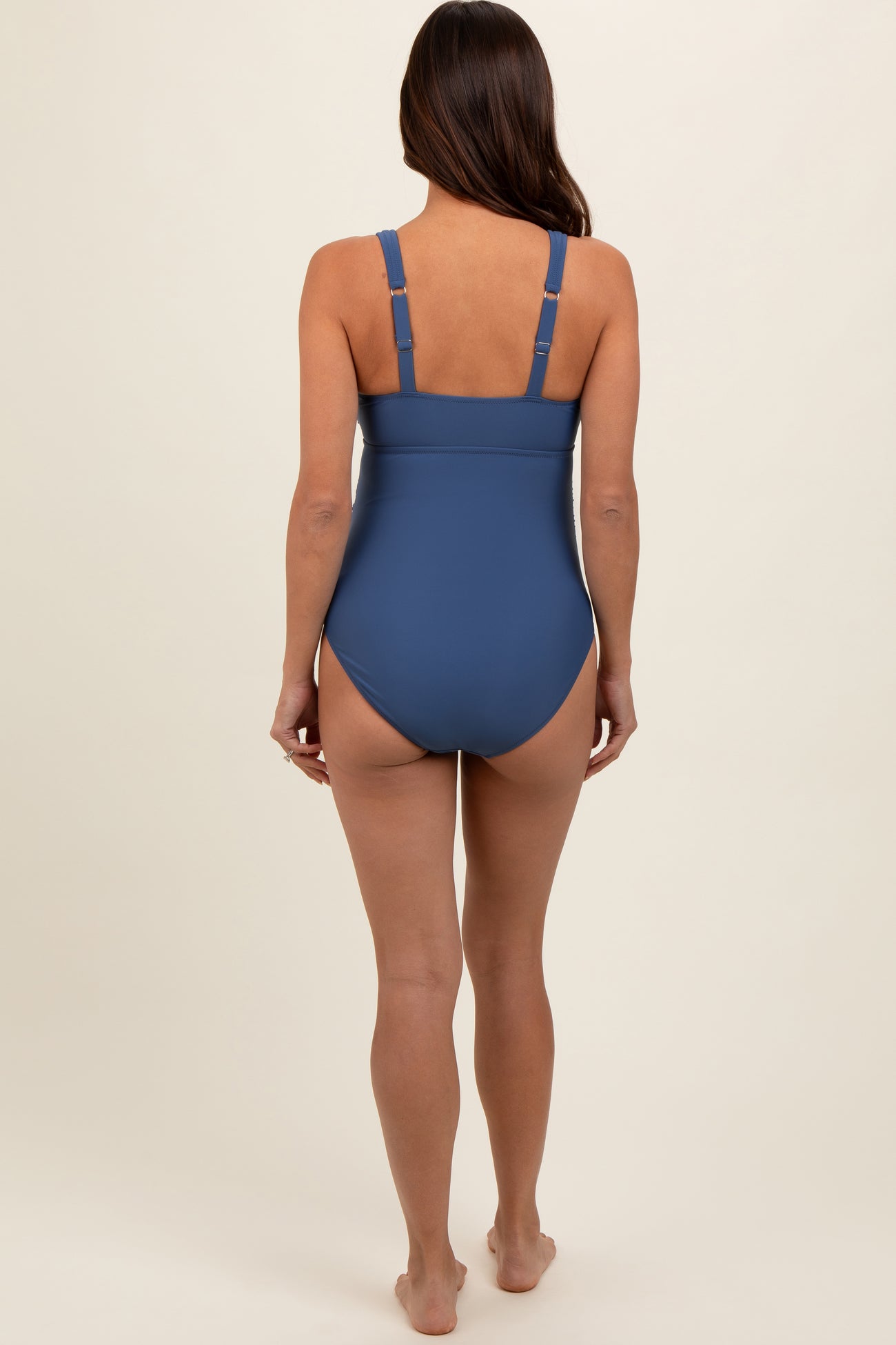 woman wearing a blue maternity swimsuit with adjustable straps, showing the back view