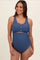 woman wearing a navy blue maternity swimsuit with scalloped edges and a cut-out design, showcasing her baby bump