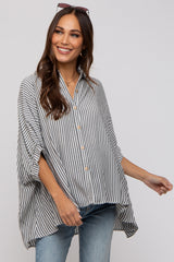 woman wearing a striped maternity top with a button-down front and relaxed fit, smiling while standing against a light background