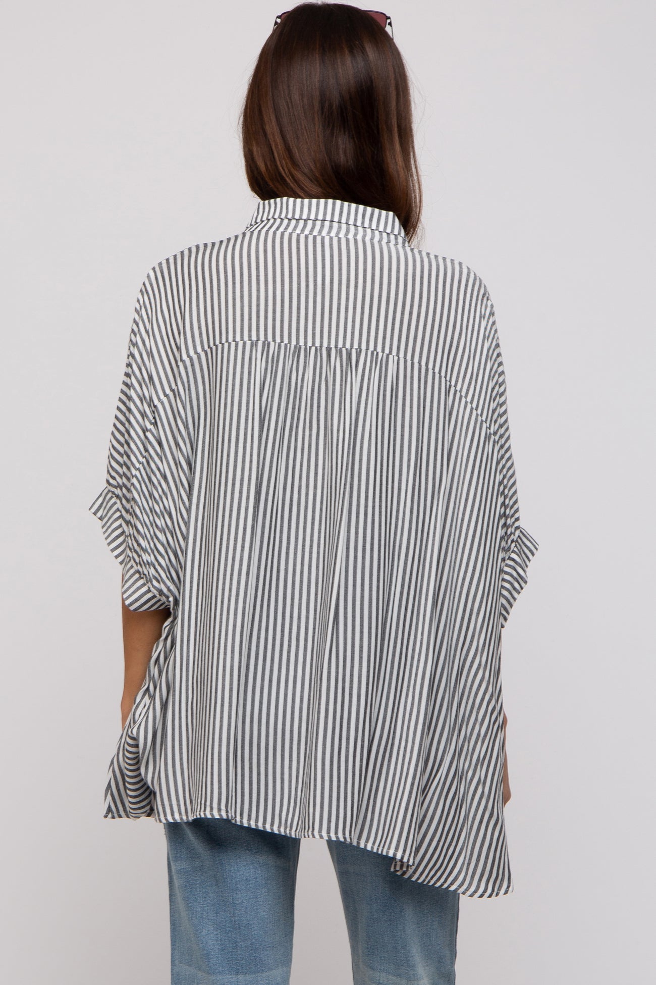 woman wearing a black and white striped maternity top with a loose, flowy fit, viewed from the back