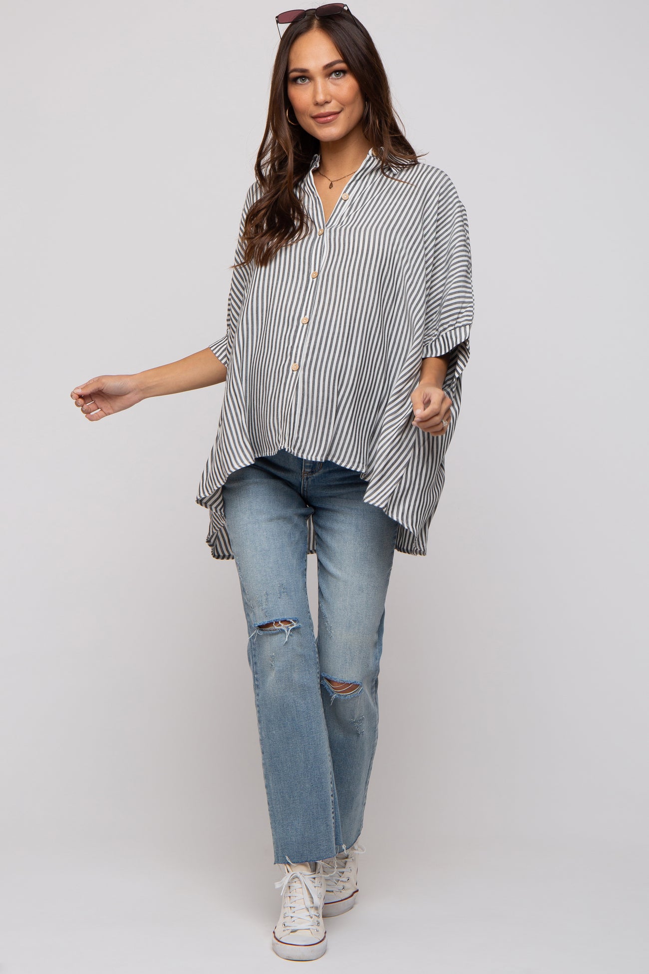 woman wearing a striped maternity top with button details and paired with ripped blue jeans