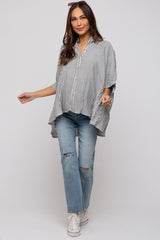 woman wearing a striped maternity top with button details and paired with ripped blue jeans