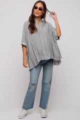 woman wearing a striped oversized maternity shirt with buttons and distressed blue jeans, styled casually with sunglasses