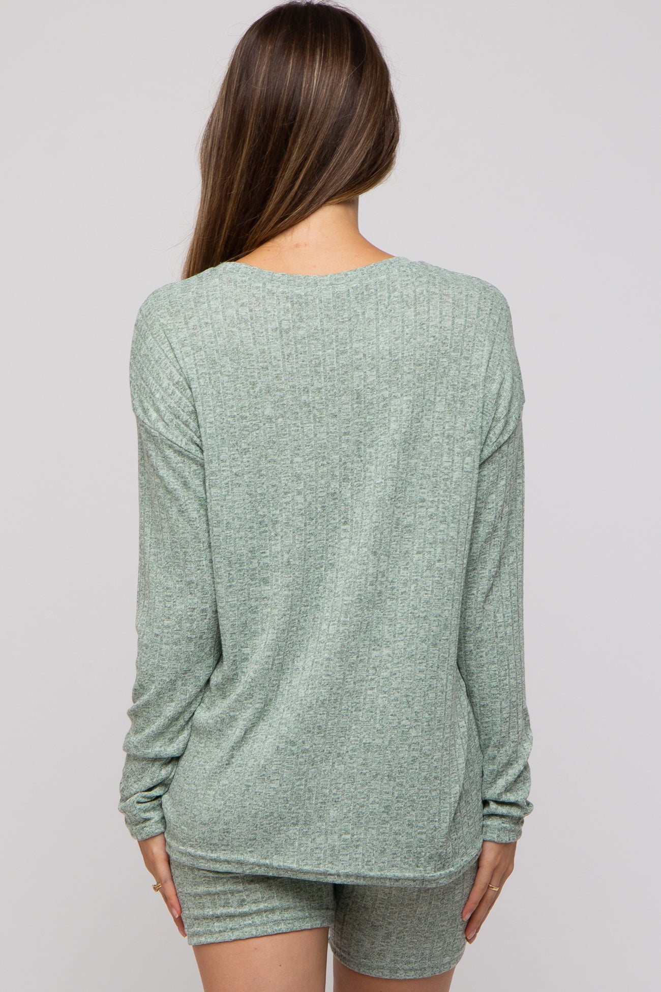 woman wearing a green ribbed maternity lounge set, view from the back showing long sleeves and shorts