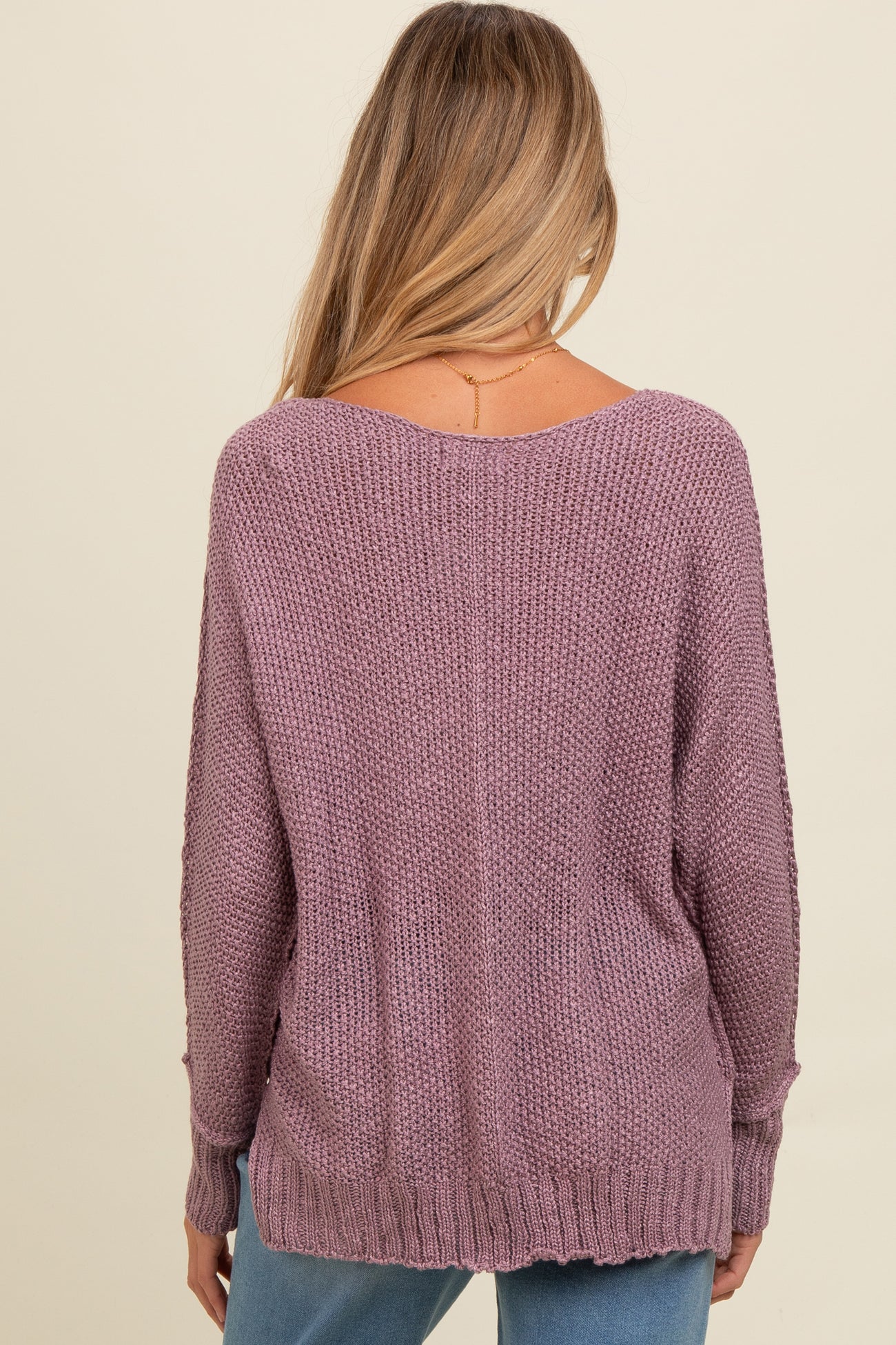 woman wearing a mauve oversized maternity sweater with a relaxed fit and ribbed hem, showing the back view