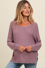 woman wearing a soft lavender v-neck maternity sweater with long sleeves and side slits, styled with light blue jeans