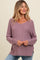 woman wearing a soft lavender v-neck maternity sweater with long sleeves and side slits, styled with light blue jeans