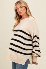 woman wearing a beige and black striped maternity sweater with a visible baby bump and side slits