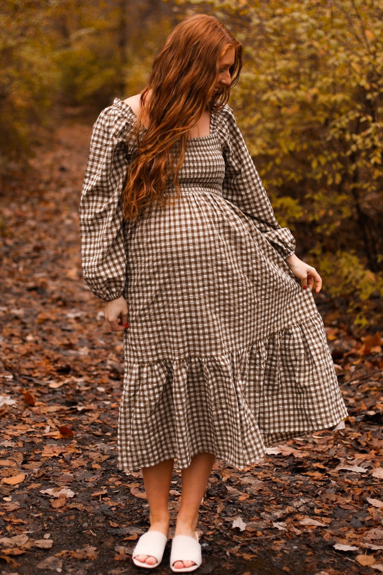 woman wearing a brown and white checkered maternity dress with long puff sleeves and a flared hem, showing her baby bump
