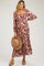 woman wearing a burgundy floral maternity maxi dress and holding a wide-brimmed hat with a baby bump visible