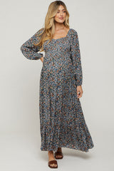 woman wearing a floral maternity maxi dress with long sleeves and a square neckline, showcasing her baby bump