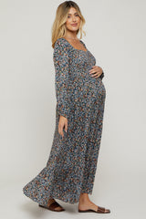 woman wearing a long sleeve floral print maternity dress, showing her baby bump, standing against a neutral background