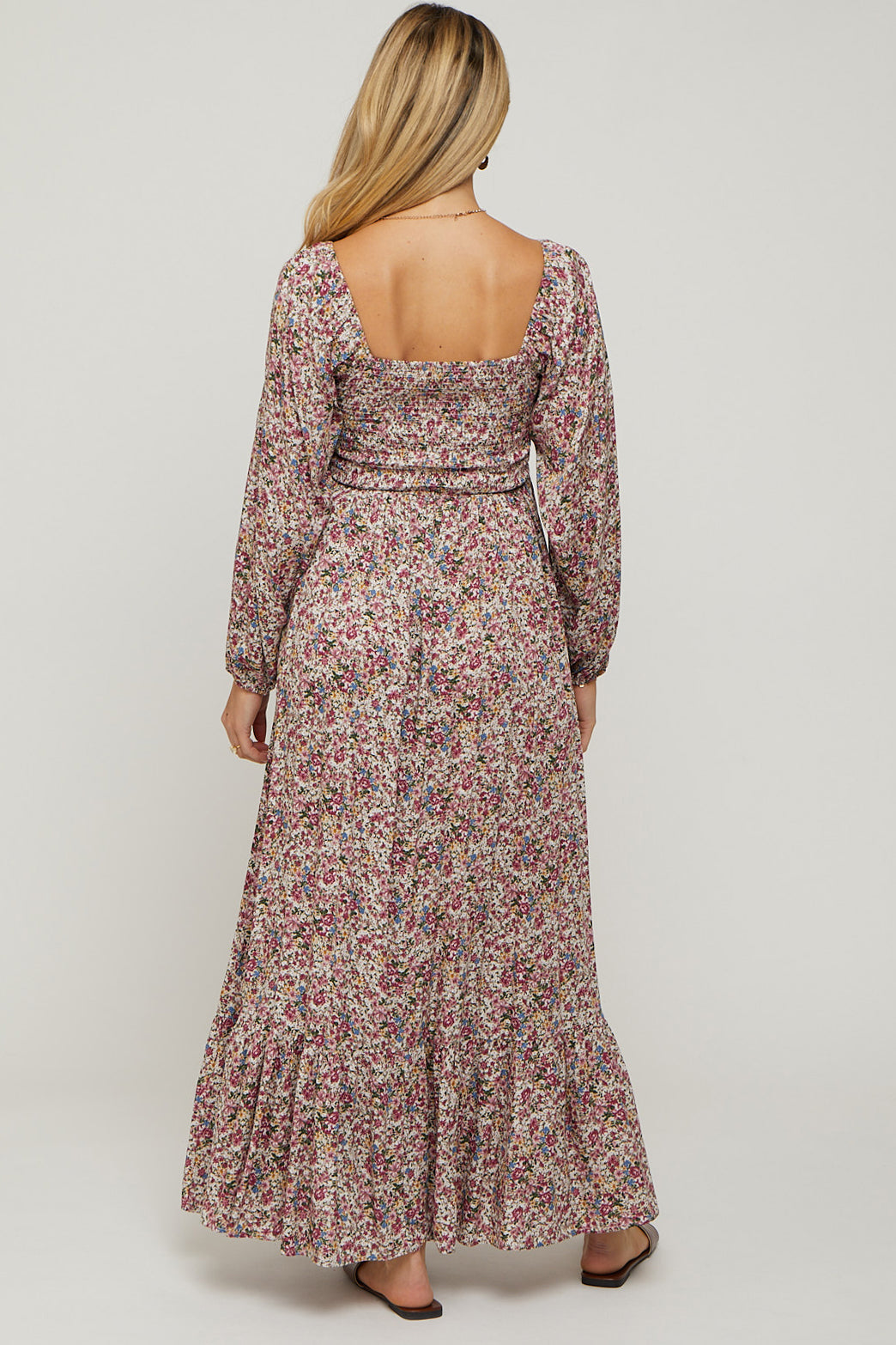 woman wearing a floral long sleeve maternity maxi dress with a fitted bodice and ruffled hemline, showing a baby bump