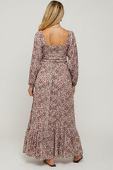 woman wearing a floral long sleeve maternity maxi dress with a fitted bodice and ruffled hemline, showing a baby bump