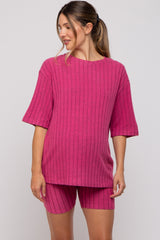 woman wearing a hot pink short sleeve maternity top and matching shorts, showing her baby bump