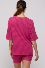 woman wearing a pink ribbed maternity loungewear set with a short sleeve top and matching shorts, showing her back