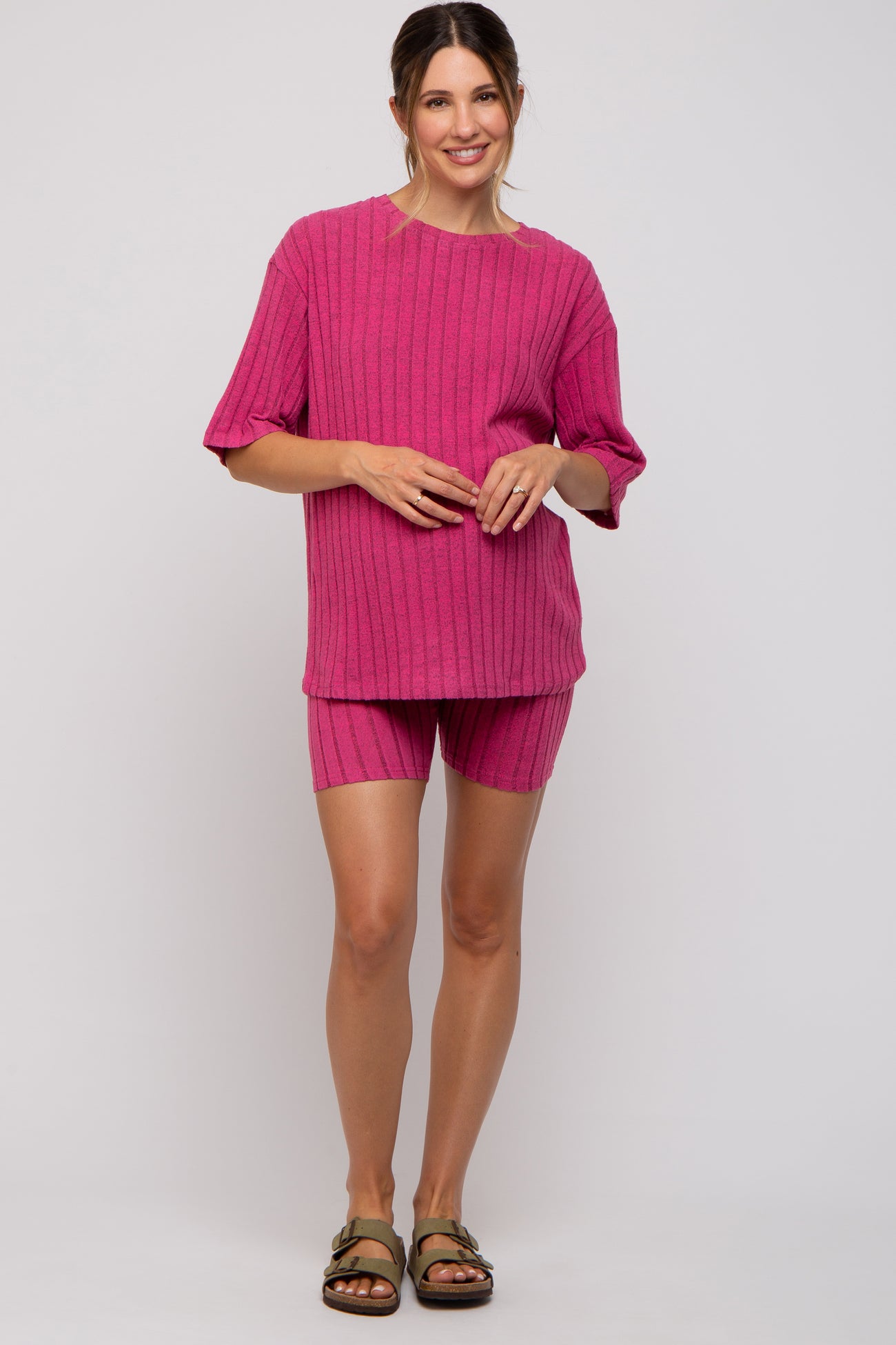 woman wearing a fuchsia ribbed maternity loungewear set with a relaxed fit top and matching shorts, showing her baby bump