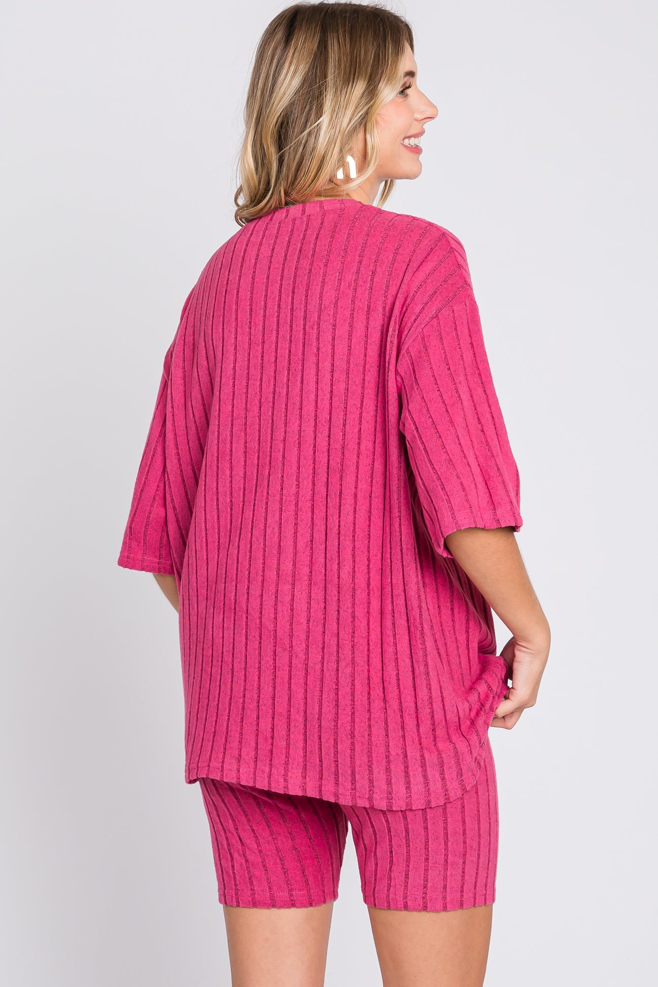 woman wearing a bright pink oversized ribbed top and matching shorts, view from the back