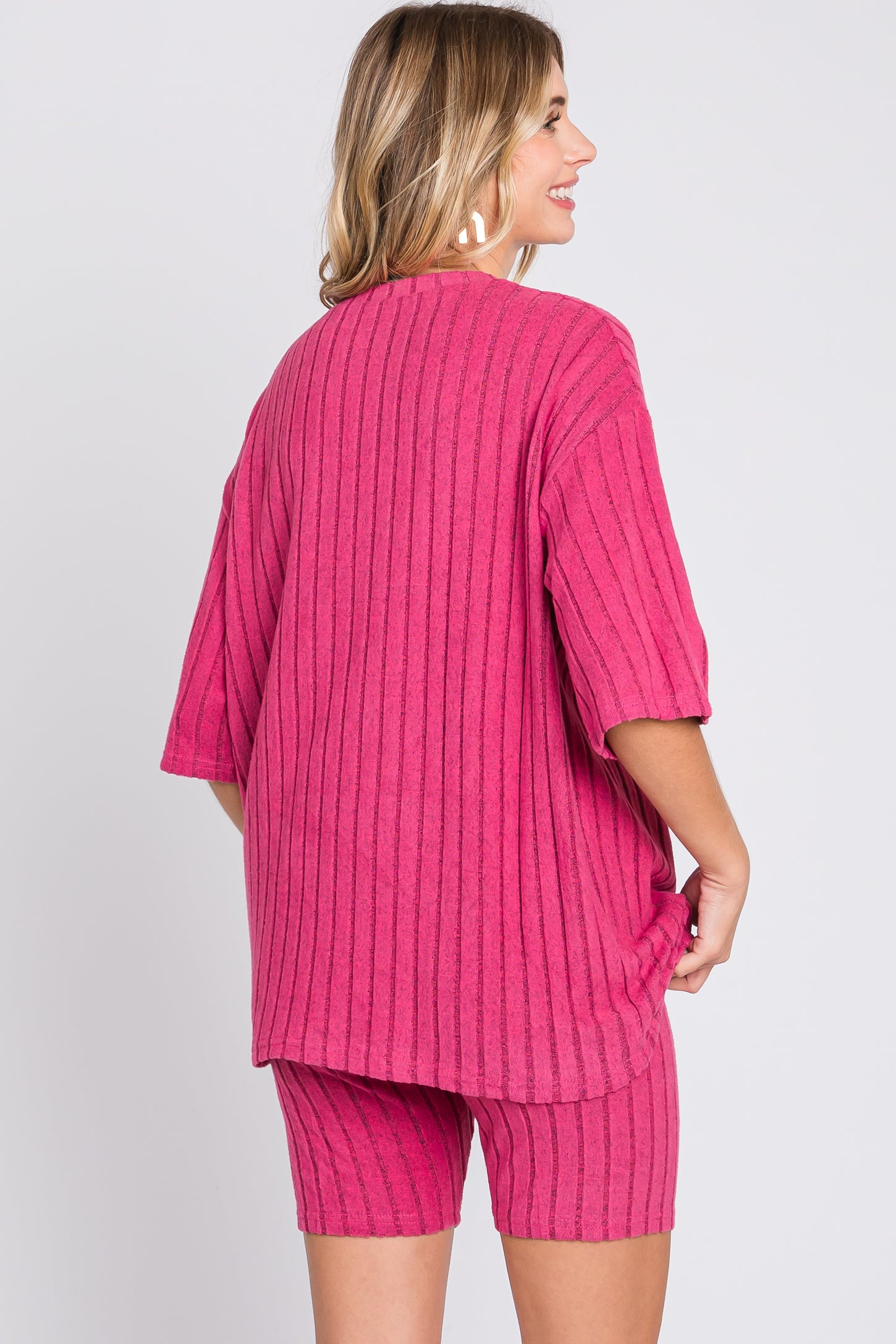 woman wearing a bright pink oversized ribbed top and matching shorts, view from the back