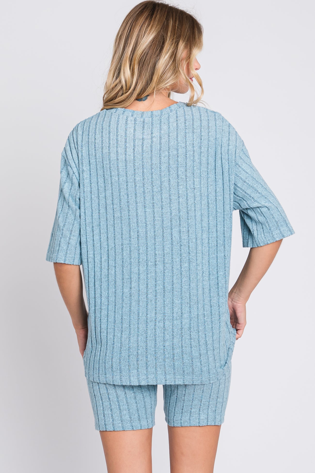 woman wearing a light blue short sleeve ribbed top and matching shorts, viewed from the back