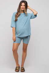 woman wearing a light blue ribbed maternity top and matching shorts, showing her baby bump