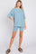 woman wearing a light blue ribbed short sleeve top and matching shorts, styled with brown slide sandals