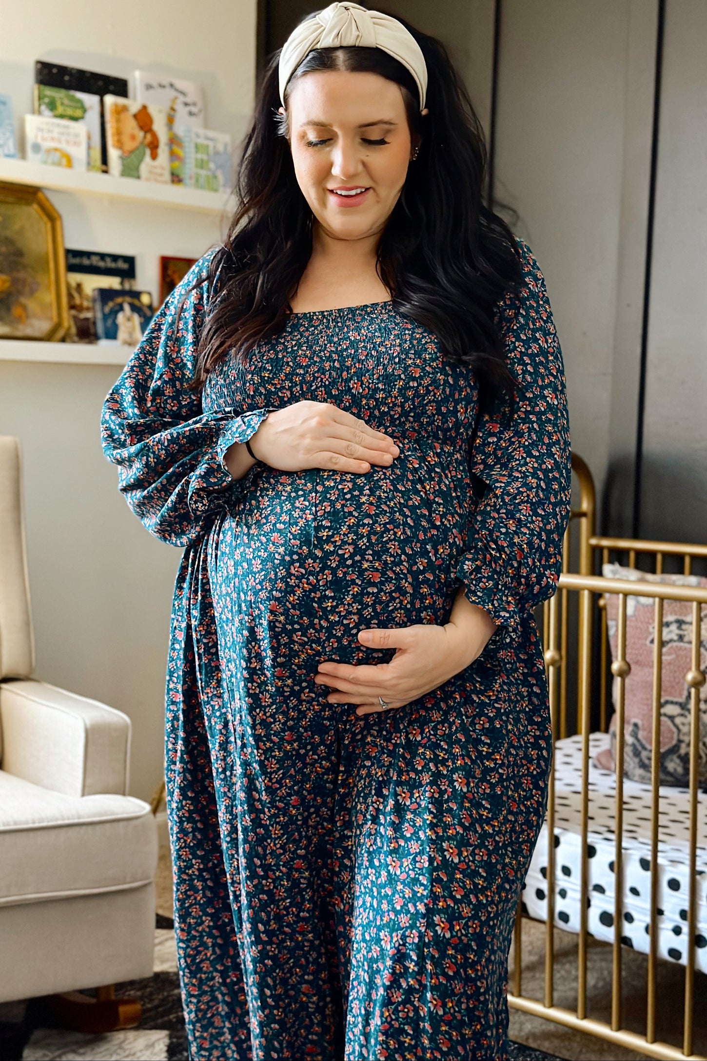 woman wearing a dark green floral maternity dress and holding her baby bump