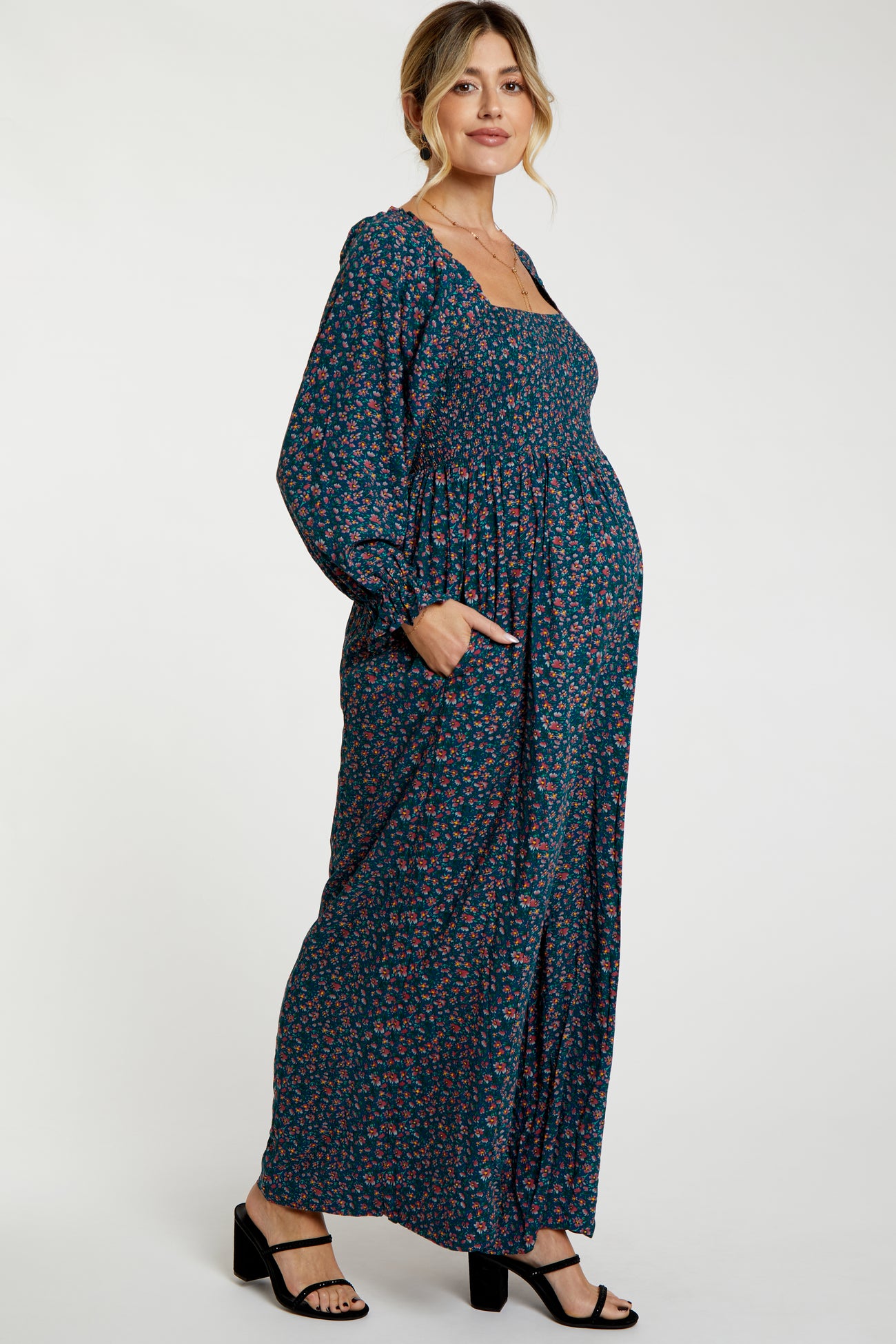 woman wearing a navy floral maternity maxi dress with long sleeves and pockets, showcasing her baby bump