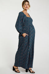 woman wearing a navy floral maternity maxi dress with long sleeves and pockets, showcasing her baby bump