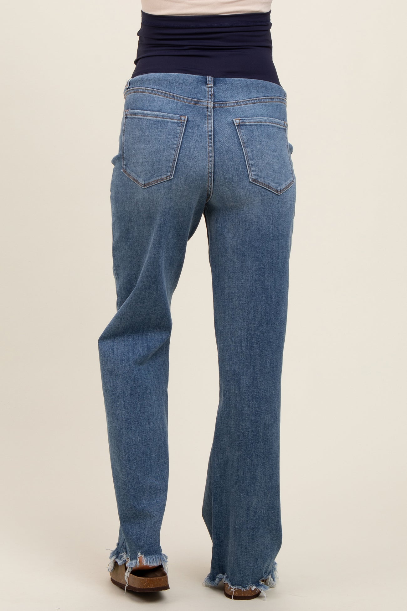 woman wearing maternity blue distressed straight leg jeans, showing the back view with a comfortable belly panel