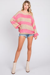 woman wearing a pink and beige striped oversized knit sweater with denim shorts and beige ankle boots