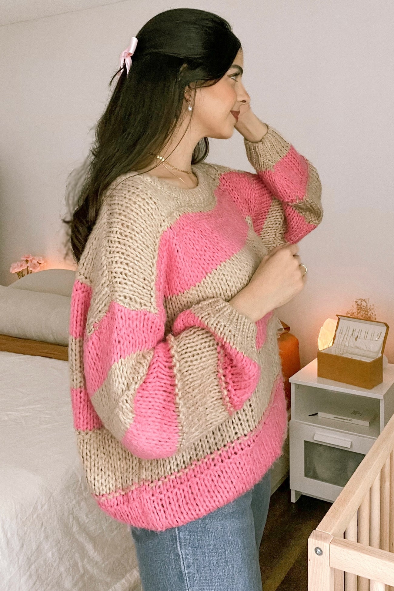 woman wearing a beige and pink striped oversized sweater with long sleeves and a casual hairstyle