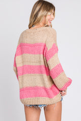 woman wearing a beige and pink striped oversized knit sweater with a loose fit and rolled sleeves