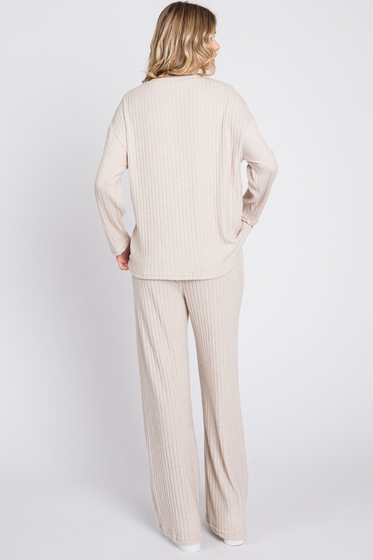 woman wearing a beige ribbed knit long sleeve top and matching wide-leg pants, view from the back