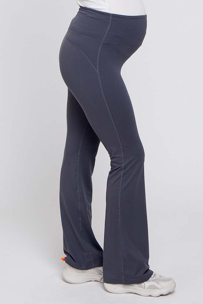 woman wearing gray maternity active pants with a fitted waist and flared legs, showcasing her baby bump