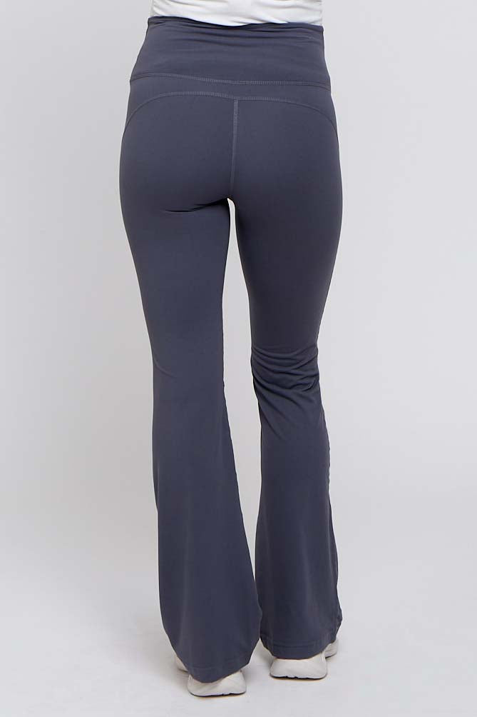 woman wearing gray maternity activewear pants with a flared hem, showing the back view