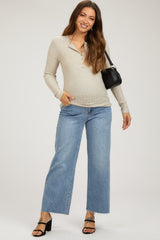 woman wearing a beige maternity long sleeve henley top with button details and high-waisted wide-leg jeans, holding a handbag