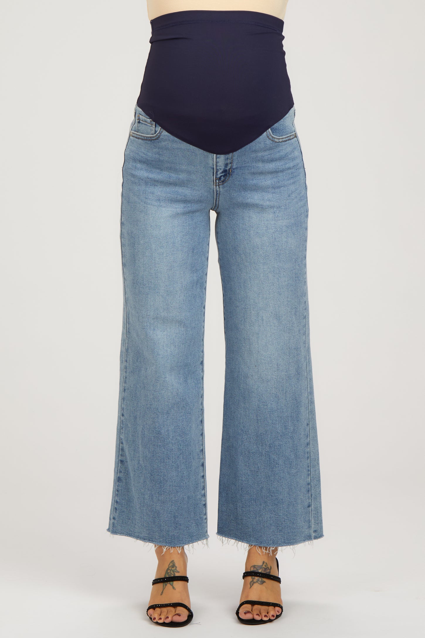 maternity wear high-waisted wide-leg jeans in light blue with a navy belly band, model wearing them with open-toed sandals