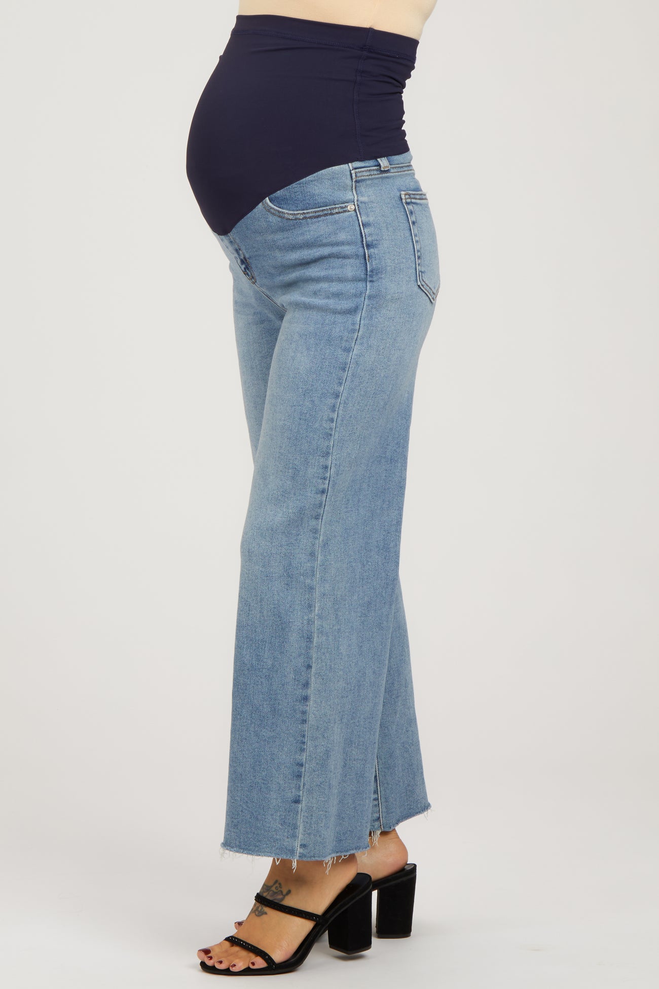woman wearing light blue maternity wide-leg jeans with a dark blue belly panel and a visible baby bump
