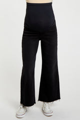 woman wearing black flared maternity jeans with a high waistband and frayed hem