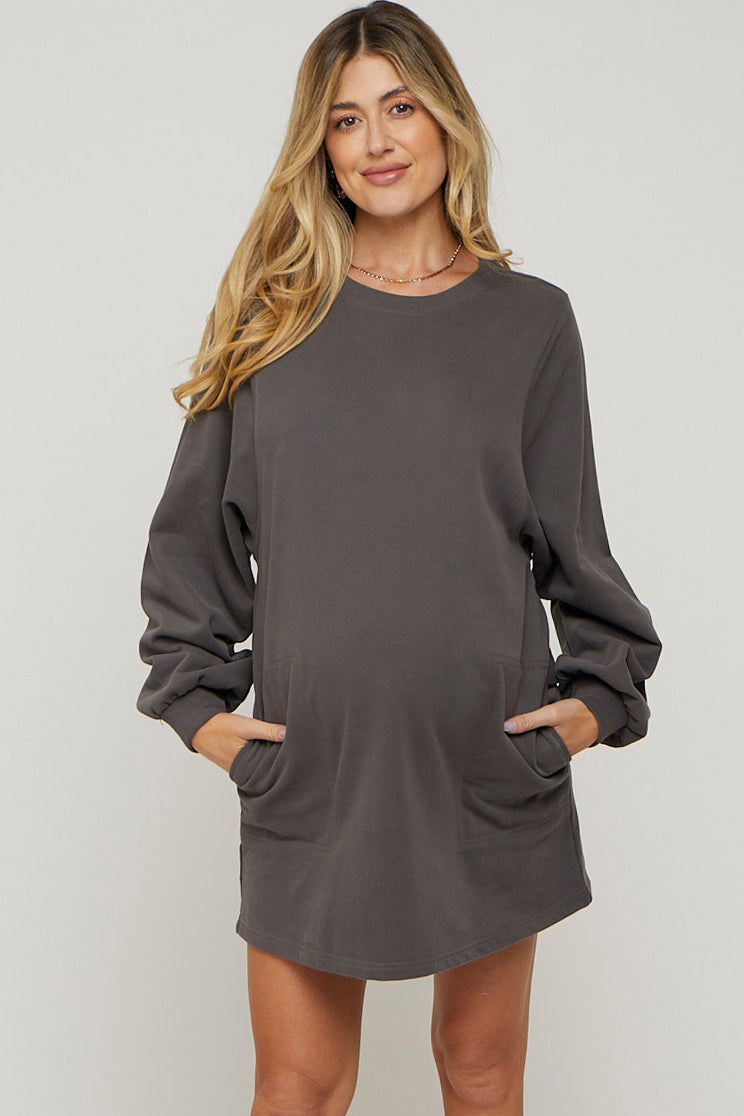 woman wearing a dark gray maternity sweatshirt dress with long sleeves and side pockets, highlighting her baby bump