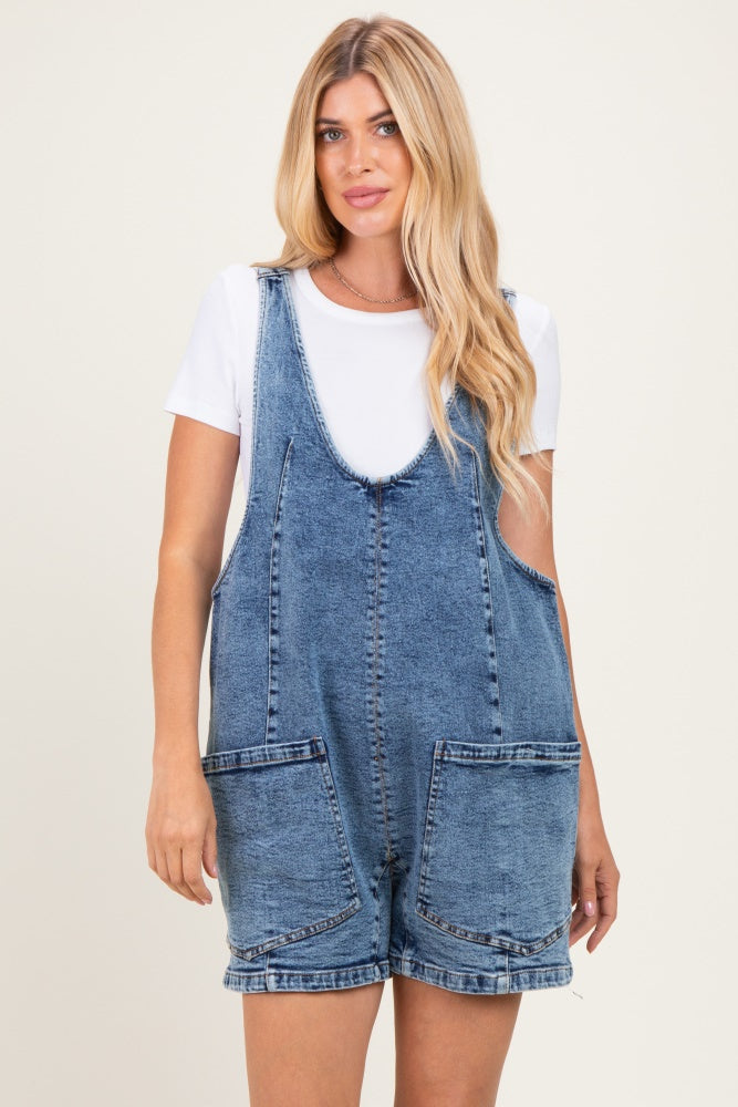 woman wearing a blue denim overall dress with large front pockets over a white t-shirt