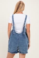 woman wearing a white short sleeve top under a blue denim overall dress, viewed from the back