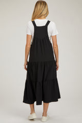 woman wearing a black maternity dress with a tiered skirt and adjustable straps, shown from the back